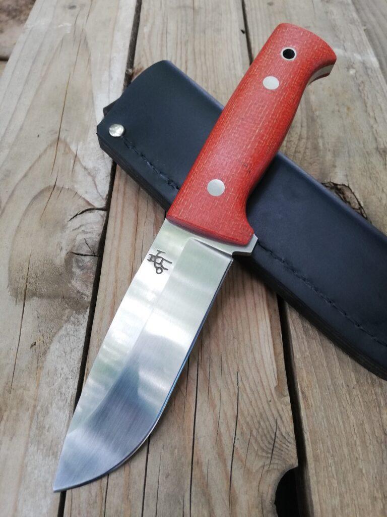 Bushcrafter 12 knife with a red handle on a black leather sheath