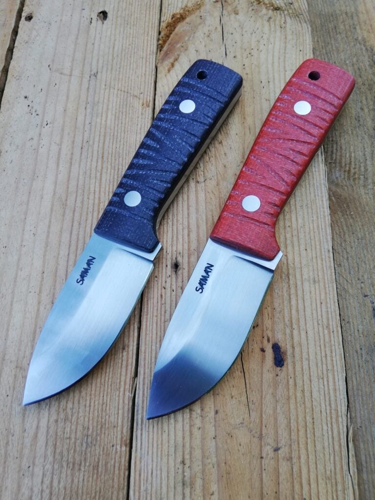 Two EDC knives with blue and red handles on weathered boards