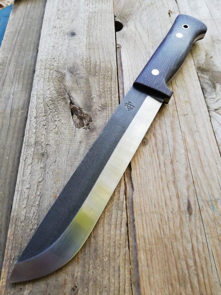 Long-bladed Leuku knife with a black handle on weathered boards