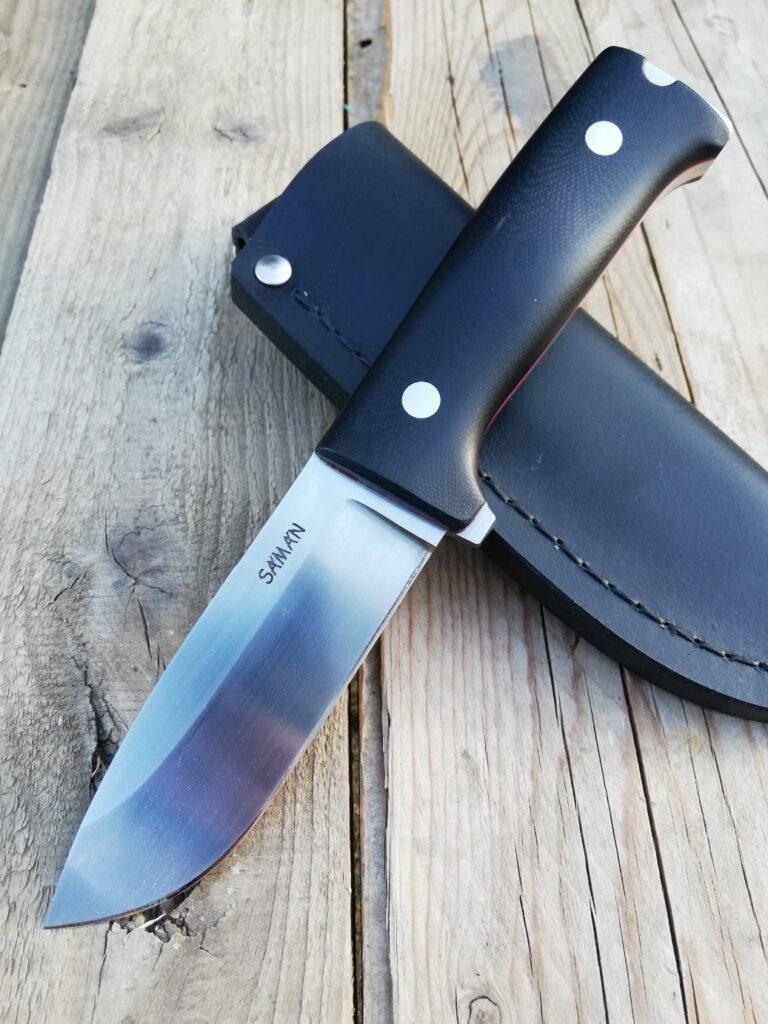 SMK military knife with a black handle on a black leather sheath
